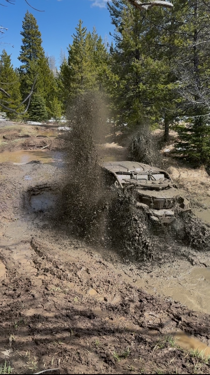 Off-road vehicle fording a stream through Montana backcountry during terrain training