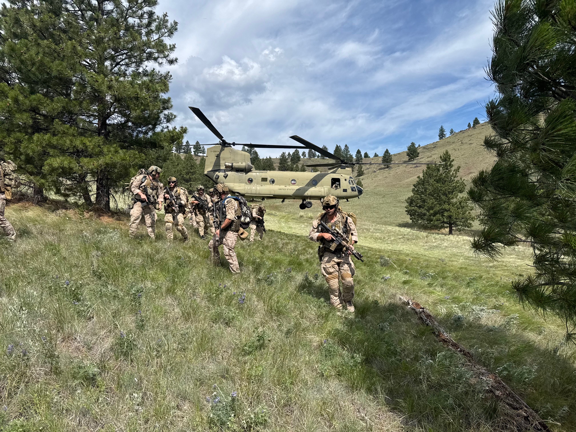 Military personnel deploying from Chinook helicopter during training at First Services Group Montana ranch